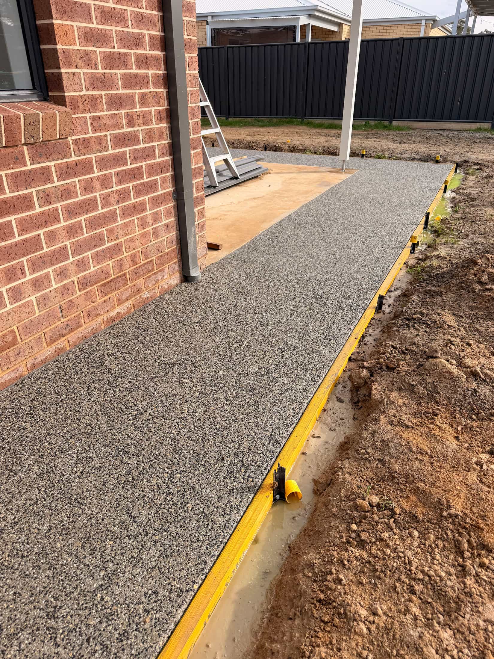Exposed aggregate concrete path beside a home by KO. Landscapes
